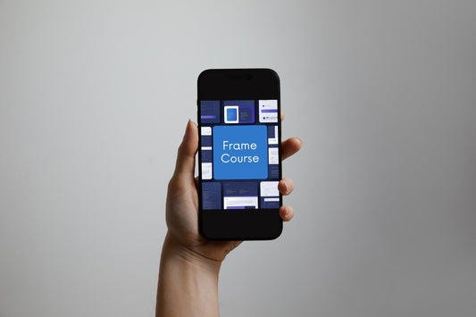 A hand holding a black smartphone against a plain light gray background. The phone screen displays a blue and white app interface titled "Frame Course.